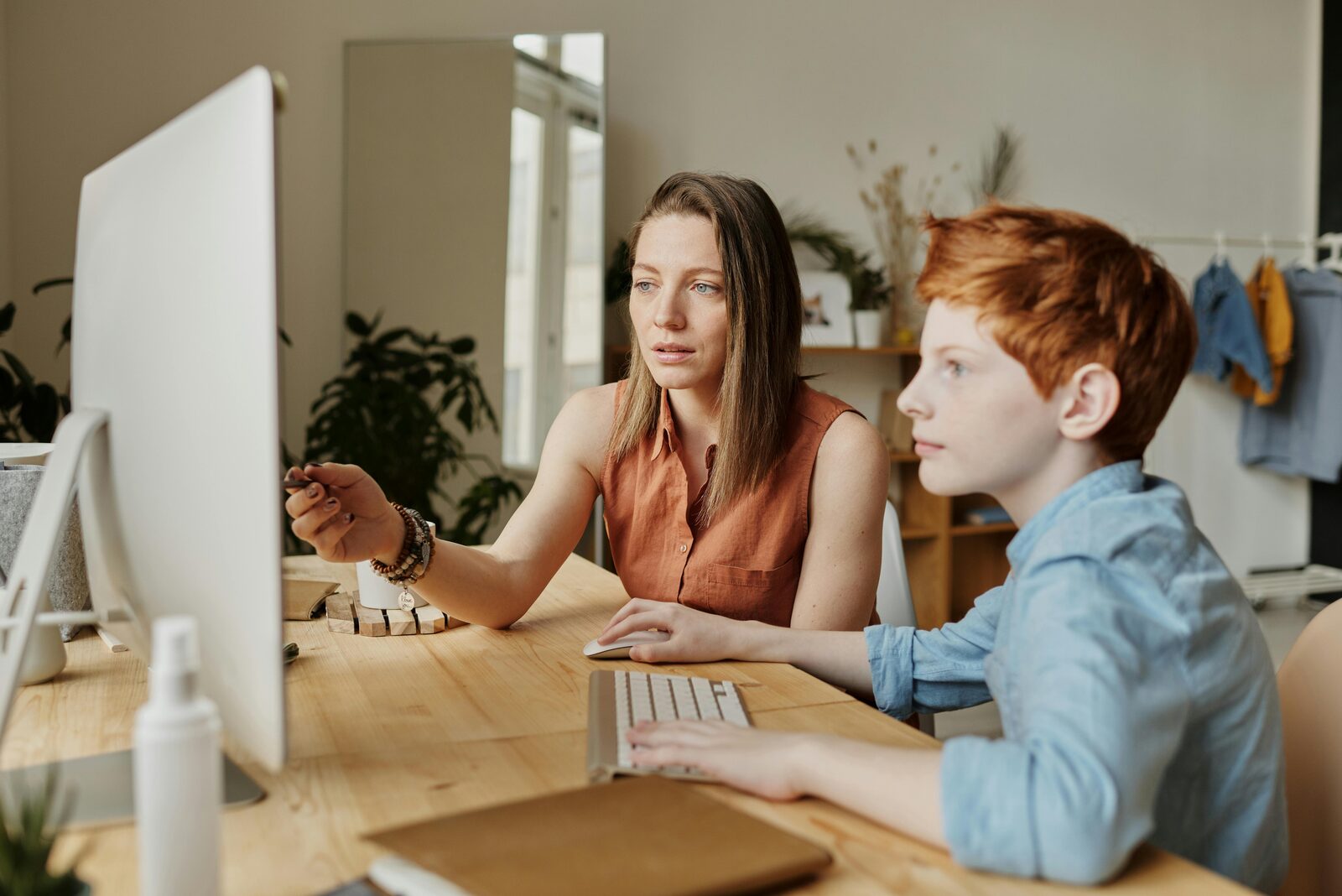 Mother helping her son at a computer screen at home