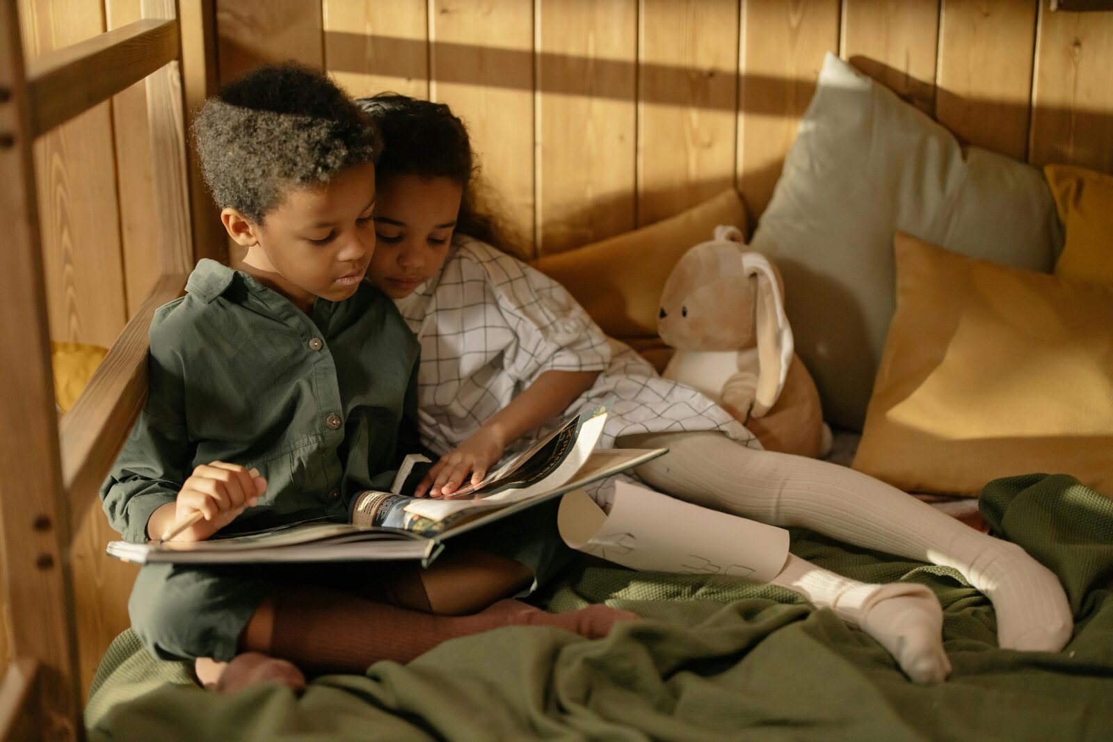 Brother and sister reading a book together in a cosy bunk bed